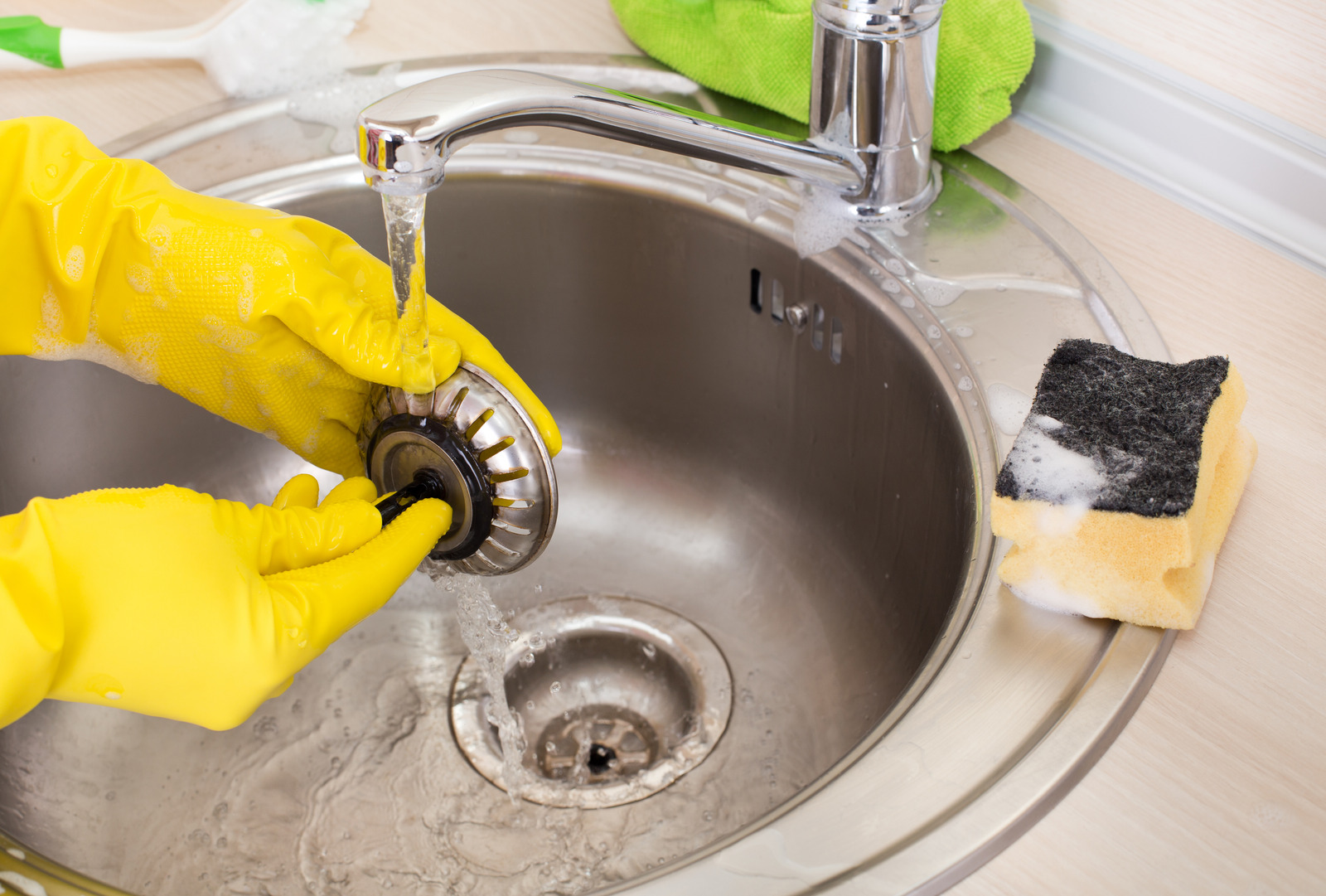 A2B Plumbing technician in Burnaby, BC, uses a drain snake to clear a clogged kitchen sink drain.